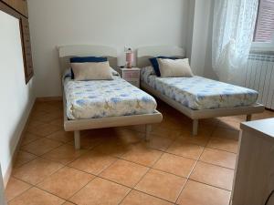 two beds sitting in a room with tile floors at EDEN. La casa di Claudia in Ronciglione