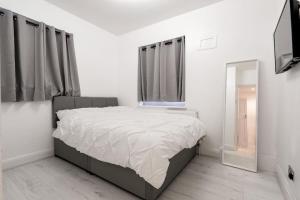 a white bedroom with a bed and a mirror at 2 Bed Apartment In Wembley, Ealing, London in Perivale