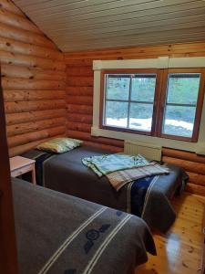 a bedroom with two beds in a log cabin at Lomamökki Haapajärven rannalla in Jyrkkä