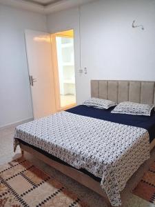 um quarto com uma cama com um edredão azul e branco em Asma em Houmt Souk