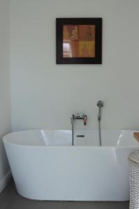 Una bañera blanca en una habitación con un cuadro. en Ocean View - The House, en Knysna