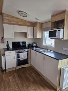 a kitchen with white cabinets and a sink and a microwave at Exquisite holidays letting for 3 nights starting from £90 in Jaywick Sands