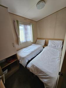 two beds in a small room with a window at Exquisite holidays letting for 3 nights starting from £90 in Jaywick Sands