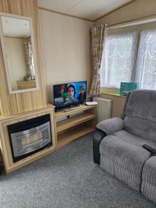 a living room with a couch and a tv and a fireplace at Exquisite holidays letting for 3 nights starting from £90 in Jaywick Sands