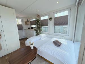 um quarto com uma cama branca e uma mesa de madeira em Tiny lake houses near the beach and centre em Zeewolde