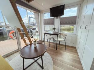 uma sala de estar com uma mesa e cadeiras e uma televisão em Tiny lake houses near the beach and centre em Zeewolde