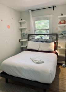 a bedroom with a bed with white sheets and a window at Serene Cottage in Halifax