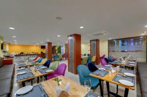 a restaurant with wooden tables and colorful chairs at Click Hotel Guwahati in Guwahati