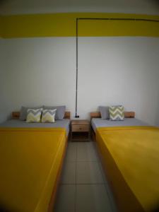 two beds in a room with yellow and white at Banana Homestay in Banyuwangi