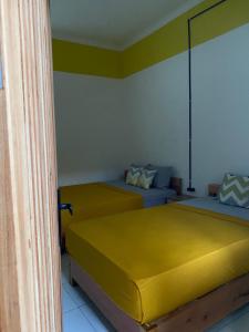 two beds in a room with yellow sheets at Banana Homestay in Banyuwangi