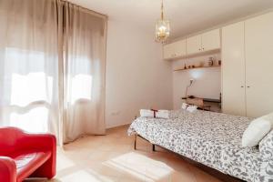 een slaapkamer met een groot bed en een rode stoel bij Caio Asinio Apartment in Napels