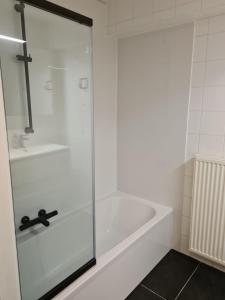 a white bath tub with a glass shower door at Tof en ruim appartement in Heist-Aan-Zee! in Knokke-Heist