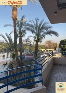 a balcony with palm trees and a blue railing at Gîte Hôtel Gezira Louxor 2 in Luxor