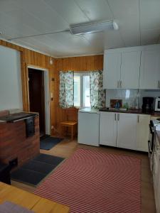 a kitchen with white cabinets and a red rug at Riverside Restplace in Tornio +3 photos