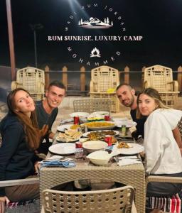 a group of people sitting around a table eating food at RUM SUNRlSE LUXURY CAMP in Wadi Rum