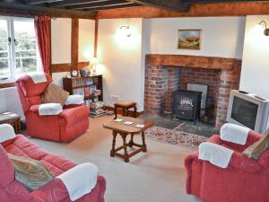 uma sala de estar com mobiliário vermelho e uma lareira em Bank Cottage em Boraston