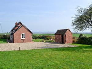 une petite maison en briques dans un champ avec une cour dans l'établissement Bank Cottage, à Boraston