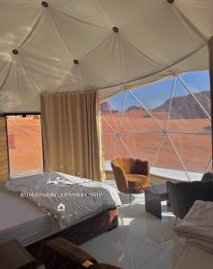 Una habitación con una cama y una silla en una tienda de campaña en RUM SUNRlSE LUXURY CAMP, en Wadi Rum