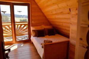 a bed in a wooden room with a large window at Highland Retreat Dzianisz in Witów
