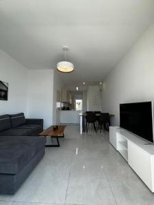 een woonkamer met een bank en een flatscreen-tv bij Seaside Bliss 1-Bed Apt in Paphos City