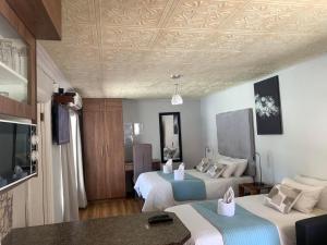ein Hotelzimmer mit 2 Betten und einem TV in der Unterkunft Victoria Oaks Guesthouse in Victoria West