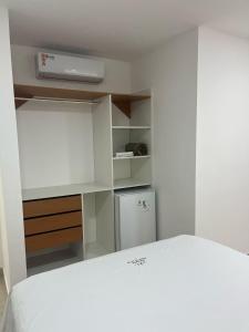 um quarto com uma cama branca e um frigorífico em POUSADA PEDRA DE JACÓ em Lauro de Freitas