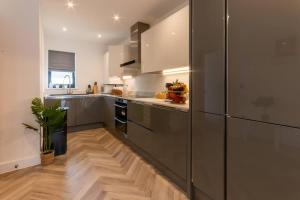 a kitchen with a stainless steel refrigerator and wooden floors at Stylish Westgate-on-sea Haven Near Beach in Margate