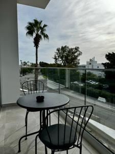 een tafel en stoelen op een balkon met een palmboom bij Seaside Bliss 1-Bed Apt in Paphos City