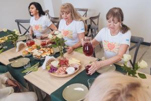 eine Gruppe von Frauen, die an einem Tisch mit Essen sitzen in der Unterkunft Zielone Podlasie Zakład Aktywności Zawodowej in Ruda