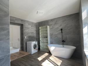 a bathroom with a tub and a washing machine at Wilson Paradise Guest House in Thenneberg