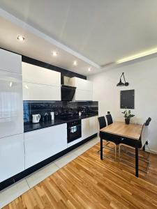 a kitchen with white cabinets and a wooden table at Piernikowy Apartament 52 in Toruń