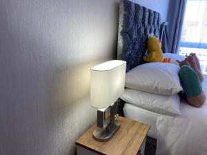 una lámpara en una mesa junto a una cama con animales de peluche en Selwyn Stays, en Liverpool