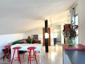 Sala de estar con mesa blanca y taburetes rojos en Alojamiento Turístico Casa Ela, en L'Aldea