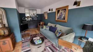 ein Wohnzimmer mit blauen Wänden und einem Sofa in der Unterkunft Après la pluie .... in Équemauville