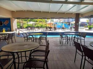 um pátio com mesas e cadeiras e uma piscina em Resort Praias do Lago Park em Caldas Novas