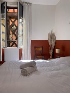 - un lit avec 2 serviettes et une fenêtre dans l'établissement Les appartements d'Albertine - Pauline, à Bourges