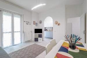 a white living room with a table and a tv at La Casa di Ciussi in Bergamo