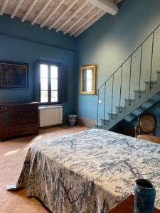 niebieski pokój z łóżkiem i schodami w obiekcie Villa Cosmiana: the gate house apartment w mieście Peccioli