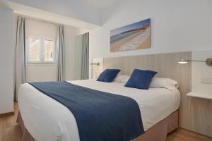 sypialnia z dużym łóżkiem i niebieskimi poduszkami w obiekcie Hotel Colonial w miejscowości Colonia Sant Jordi