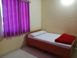 a small bed in a room with a purple curtain at Vrundavan in Panchgani