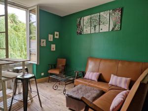Una sala de estar con un sofá y una pared verde. en Le jardin aux camélias, en La Roche-sur-Yon