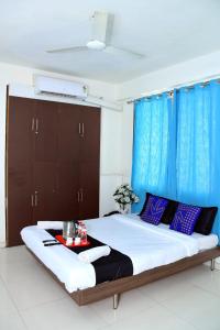 a bedroom with a large bed with blue curtains at Hotel Pristine,Pune in Pune