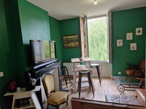 Una sala de estar verde con televisión y chimenea. en Le jardin aux camélias, en La Roche-sur-Yon 31 fotos más