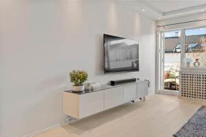 un soggiorno con TV su una parete bianca di Central Oslo - Lovely 2 bedrooms flat with balcony a Oslo