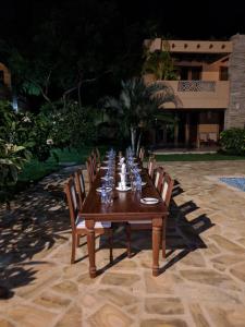 a long wooden table with chairs and drinks on it at Villa Mandhari - Diani Beach in Diani Beach