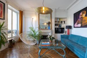 a living room with a blue couch and a table at Marais Magique: Exclusive Apartment in Paris in Paris