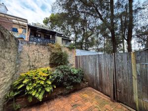 a wooden fence with some plants and flowers at Cozy bedroom in terrace house in Sydney