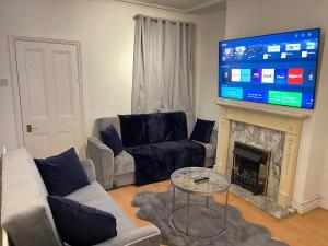 a living room with a couch and a fireplace with a flat screen tv at Hometel Nice Comfy Apartment Can Sleep 9 in Leicester
