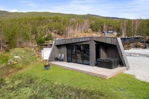 osoba stojąca w trawie przed domem w obiekcie Sogndal Fjordpanorama - Studio Cabins With View w mieście Sogndal