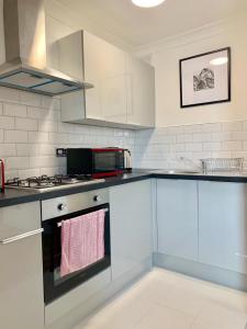a kitchen with white cabinets and a stove top oven at Chancery Lane Residenses in London